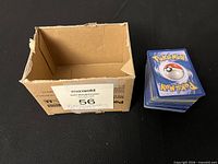 Stack of Pokémon cards next to small open cardboard box
