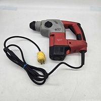 Full view of Milwaukee rotary hammer with attached cord and yellow site plug adapter