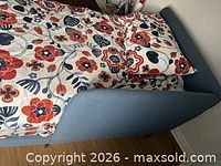 Overall view of blue upholstered twin daybed with patterned bedding