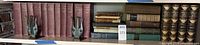 Shelf with maroon cloth volumes, brass lyre bookends and assorted books