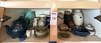 Overall view of two-shelf lot showing assorted stoneware pieces