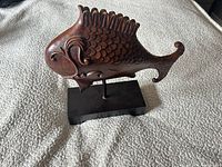 front view of carved wood fish on stand