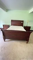 Full view of assembled queen sleigh bed frame with mattress and bedding