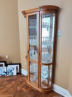Full view of oak curio cabinet showing glass door, curved glass sides, wood frame and interior shelves