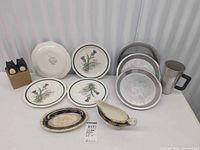 Group shot displaying all items: plates, gravy boat, oval dish, pie pans, metal mug, cat shakers