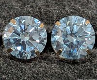 Close-up of both round diamonds in gold prongs