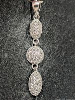 Full view of the pendant front showing three pavé links and bail