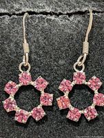 Close view of both earrings hanging on black background