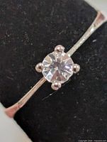 Close view of ring front showing clear stone in four-prong setting