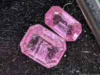 Close-up of two emerald-cut pink sapphires showing facets and color