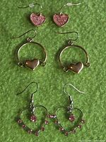 All three pairs of heart earrings on green background