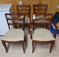 Front view of all four mahogany ladder-back chairs showing fabric seats