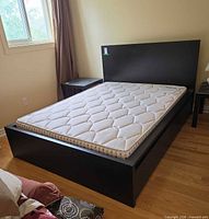 Full view of assembled black MALM bed with mattress