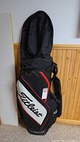Front view of black, white, red Titleist cart bag with rain hood attached