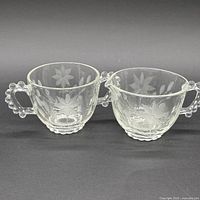 front view of matching creamer and sugar bowl showing etched motif and handles
