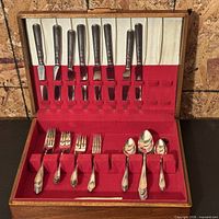 Open flatware case showing 7 knives, 2 forks, 5 spoons in red felt interior