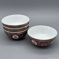 Four stacked red longevity pattern bowls showing exterior and interior