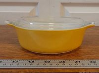 Side view showing yellow exterior, clear lid, scale for size