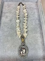 Full view of pearl necklace with cameo pendant laid flat in case