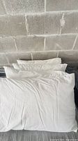 Stack of white pillows with covers against concrete wall