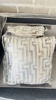 Two geometric patterned cushions wrapped in protective film