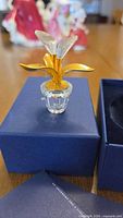 Figurine on box lid showing clear crystal pot and gold-tone leaves
