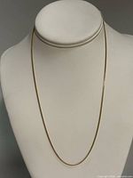 Full view of gold chain necklace on display bust