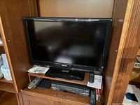 Front view of Philips 32-inch LCD HDTV on shelf with remote on stand