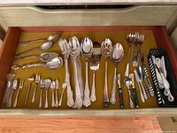 Lower drawer showing assorted serving utensils and small flatware pieces