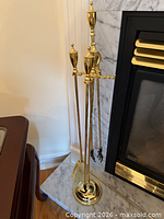 Brass fireplace tool set on stand beside fireplace