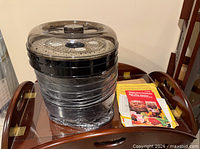 Shrink-wrapped dehydrator with lid and paperwork beside it