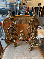 Full view of both gold-tone plastic wall sconces on chair showing overall design and candle holders