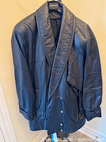 Front view of black leather jacket on hanger