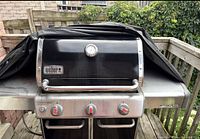 Front view of Weber Genesis Special Edition BBQ, cover pulled back to show hood, thermometer, control knobs and side shelves