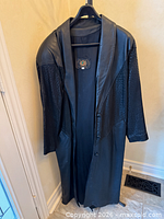 Full view of black leather long coat on hanger showing length, buttons, lapel