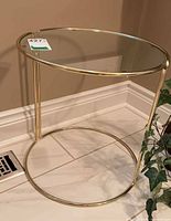 Angled view of full side table showing glass top and gold metal frame