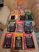 All nine boxed Atari 2600 games laid out on chair, cartridges visible on top of boxes