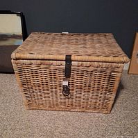 Front view of wicker trunk showing leather buckle strap and weave