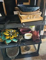 Overall lot on shelving showing trays, rattan tray, placemats, metal flower art and tin