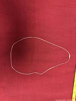 Full view of coiled silver snake chain on red background