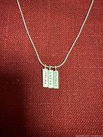 Full view of necklace showing three word pendants and chain