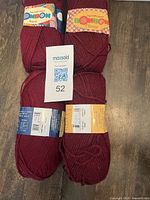 Stack of four burgundy Bonbon yarn skeins with labels