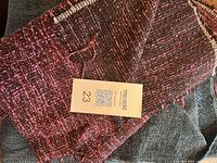 Pink magenta bouclé remnant on top of teal herringbone fabric with MaxSold tag visible