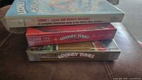 Three sealed hardcover Looney Tunes books stacked