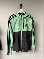 Front view of Adidas mint green and black hooded jacket on hanger