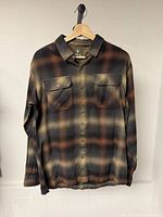 Front view of Kuhl plaid flannel shirt hanging on hanger