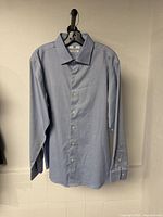 Front view of light blue Uniqlo long sleeve dress shirt hanging on hanger