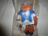 Front view of sealed Fozzie Bear hockey plush showing jersey, stick and tag
