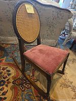 Three-quarter side view showing cane back, seat upholstery and rocker rails