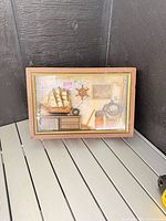 Closed box showing glass lid with nautical miniatures